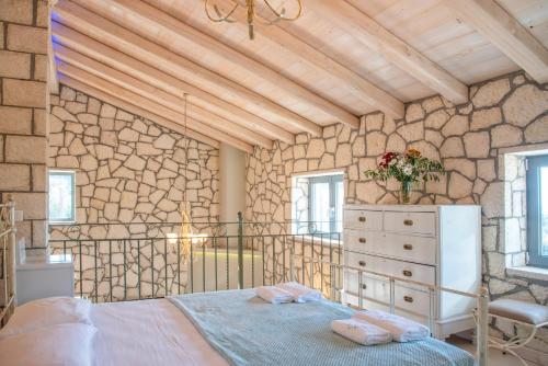 a bedroom with a bed and a stone wall at Villa Irida by Elayan Villas Corfu in Sidari