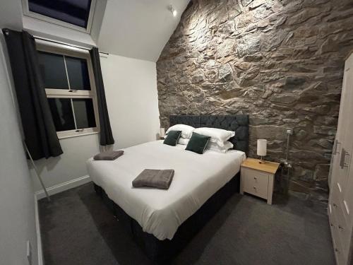 a bedroom with a large bed and a stone wall at 2 bed house sleeps 4 centre of Welshpool Parking in Welshpool