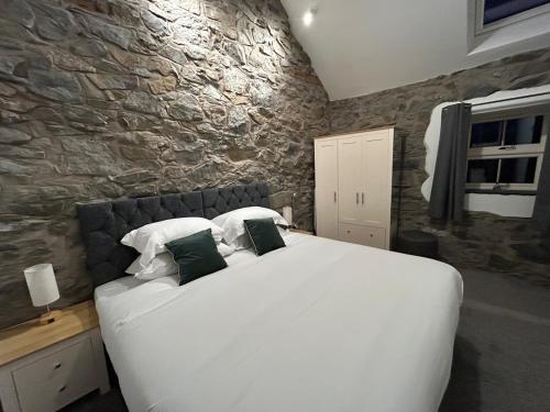 a bedroom with a large white bed with a stone wall at 2 bed house sleeps 4 centre of Welshpool Parking in Welshpool
