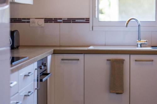 una cocina con armarios blancos y un fregadero en Juine, en Fargues