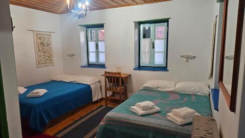 two beds in a room with two windows at Βωλίτης Ξενώνας - Παραδοσιακό Καφενείο Ζαγορίου in Papingo