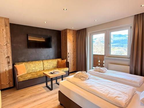 a hotel room with two beds and a couch at Aparthotel Bergland in Söll