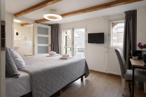 a bedroom with a bed and a desk and a television at King's Inn City Hotel Alkmaar in Alkmaar