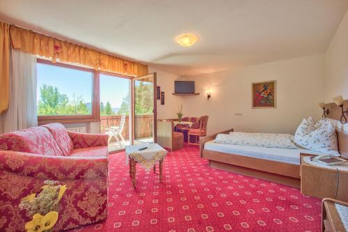 a bedroom with a bed and a couch and a chair at APIPURA hotel rinner in Soprabolzano