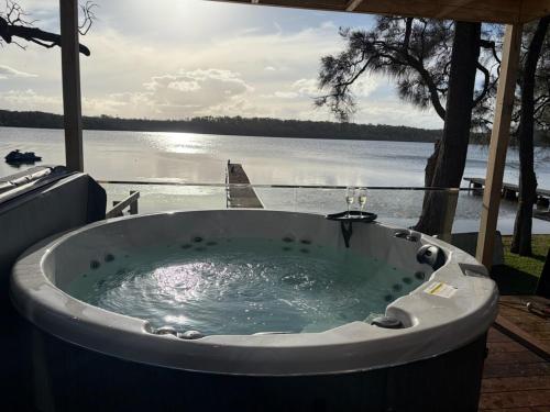 a bath tub with a view of a lake at Jerrinja - Absolute waterfront with jetty - 5 mins to Hyams Beach in Erowal Bay