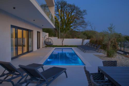 a swimming pool in a yard with chairs and a house at Villa Sensei in Linardići