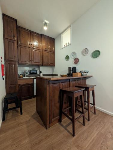 a kitchen with wooden cabinets and a table and stools at Beautiful Infante Apartment in Porto