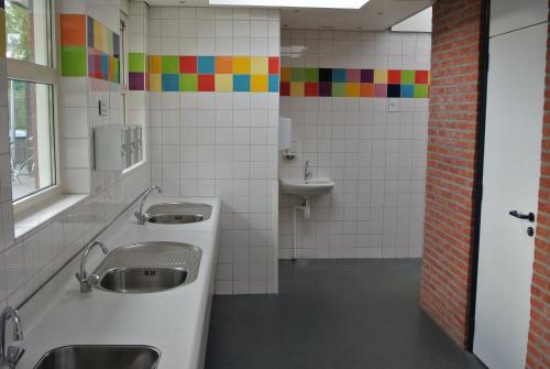 a bathroom with two sinks and a toilet and a sink at Lodge 6 personen op Camping Mounewetter in Witmarsum