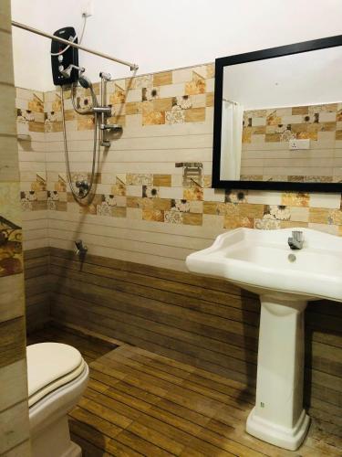 a bathroom with a sink and a toilet and a mirror at Singha Holiday Bungalow in Ibbagomuwa