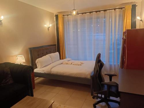 a bedroom with a bed and a window with a chair at Legatus Cozy Studios B - Ongata Rongai Furnished Apartment with Swimming pool in Nairobi