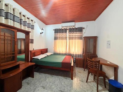 a bedroom with a bed and a desk and a bed sidx sidx sidx at Singha Holiday Bungalow in Ibbagomuwa