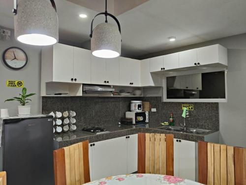 a kitchen with white cabinets and a black refrigerator at MEEK'S VILLAS TRANSIENT HOUSE in Baguio