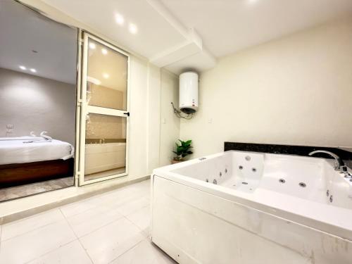 a white bathroom with a tub and a bed at Glory Pyramids Inn in Cairo
