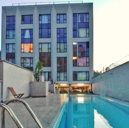 a building with a swimming pool in front of a building at Legatus Cozy Studios B - Ongata Rongai Furnished Apartment with Swimming pool in Nairobi