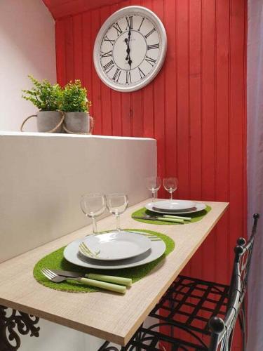a table with glasses and a clock on a wall at Studio gare et commerces sur place in Nogent-lʼArtaud