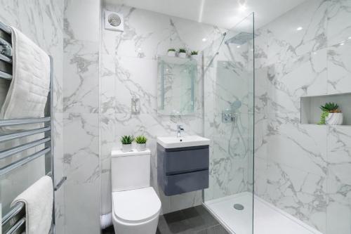a white bathroom with a toilet and a shower at Minster's Reach Apartments -Stylish City-Centre Retreat's in York
