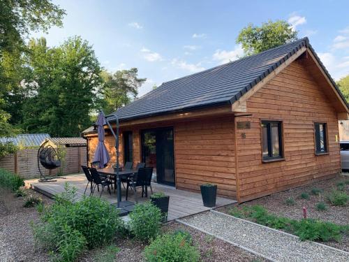 a small wooden cabin with a table and chairs at Chalet Liquidambar in Zutendaal