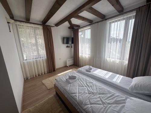 a bedroom with a large bed and two windows at Панорамна гледка in Leshten