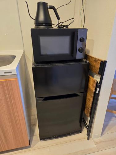 a microwave oven sitting on top of a refrigerator at Karawaru Stay 亀有 A102 in Tokyo