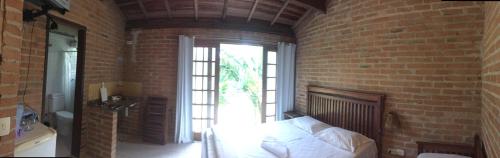 a brick walled bedroom with a bed and a window at Flats Vila Vitoria Residencial in Camburi