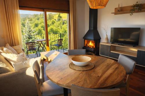 a living room with a wooden table and a fireplace at Allotjaments Vall de Muntanyes in Molló