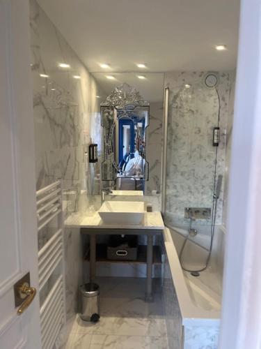 a bathroom with two sinks and a shower and a mirror at Hotel Cluny Square in Paris