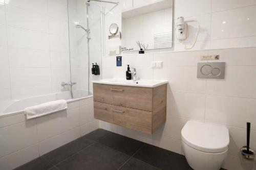 a white bathroom with a toilet and a sink at King's Inn City Hostel Alkmaar in Alkmaar