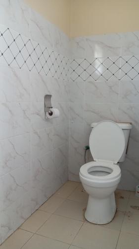 a bathroom with a toilet and a roll of toilet paper at KiQao in Nakuru