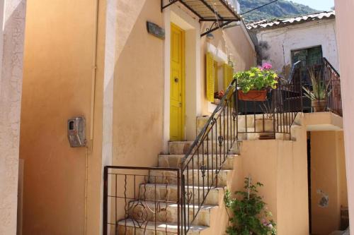 a yellow door on a building with stairs at Nature Habitat and Artistic Room in Pentátion