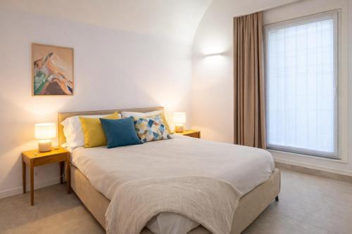 a bedroom with a large bed with two lamps and a window at Erbusco Charme Apartment in Erbusco