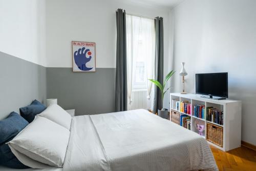 a white bedroom with a bed and a tv at Casa Strehler in Trieste