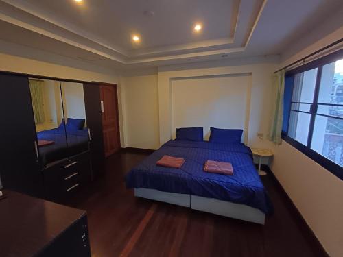 a bedroom with a bed with blue sheets and a window at Skippers inn pier 55 Bar&Guesthouse in Hua Hin