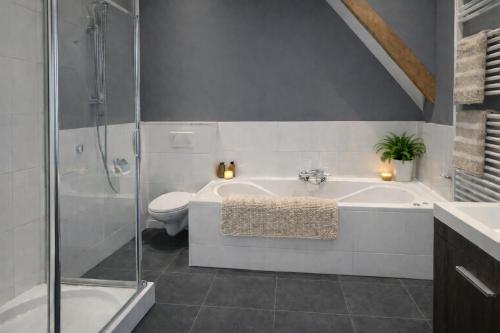 a bathroom with a shower and a tub and a toilet at Ballumerhoeve Finn lodge in Ballum
