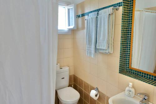 a bathroom with a toilet and a sink and a mirror at Villa G - Kamari Village in Kastraki