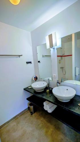 a bathroom with two sinks and a large mirror at Hôtel Restaurant du Plomb du Cantal in Murat