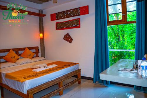 a bedroom with a bed and a table and a window at Thuru Airport Apartment in Seeduwa