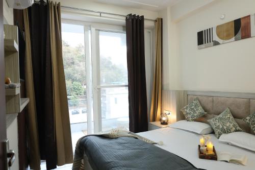 a bedroom with a bed and a large window at Solskyhaus in Rishīkesh