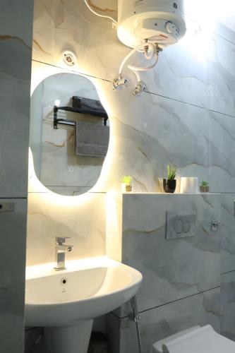 a white bathroom with a sink and a mirror at Solskyhaus in Rishīkesh