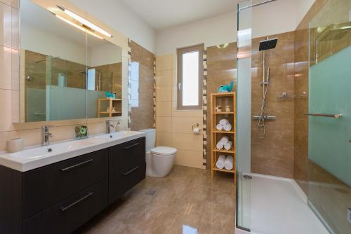 a bathroom with a sink and a shower and a toilet at Villa Aelia in Afantou