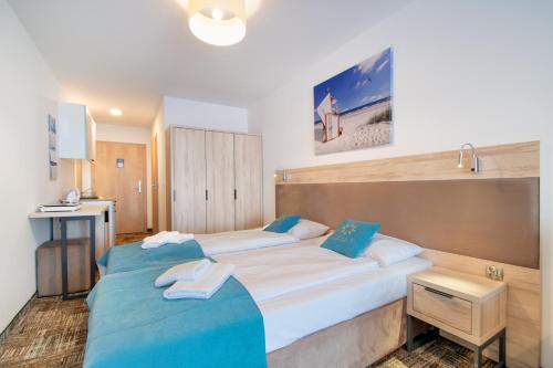 two beds in a hotel room with blue sheets at RentPlanet - Welle Resort in Grzybowo