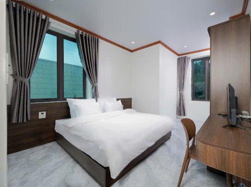a bedroom with a bed and a desk and a television at Phố Cổ Legend Hotel in Phúc Lộc