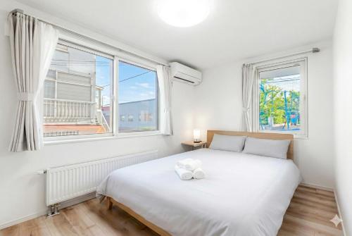 a bedroom with a white bed and two windows at THE SUN in Sapporo