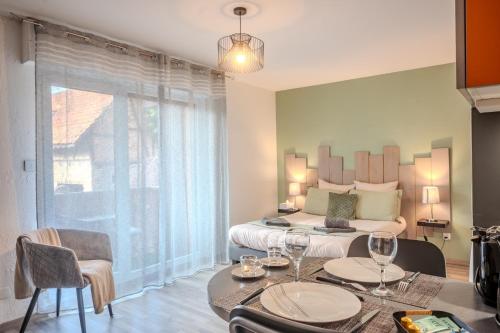 a bedroom with a bed and a table with wine glasses at Ma Préférence - Studio Cozy - Parking Gratuit - Proche Commerces & Transports in Horbourg