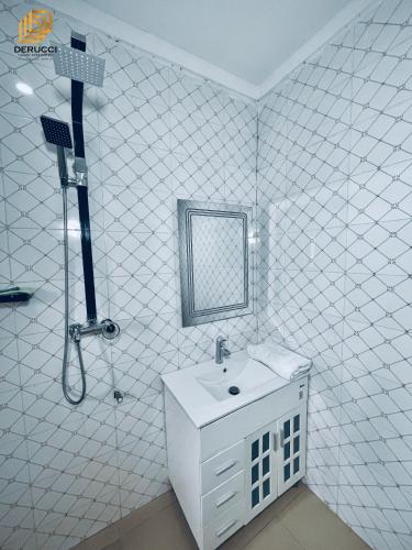 a white bathroom with a sink and a shower at Derucci Luxury Apartment in Owerri