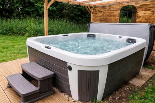 a jacuzzi tub in a backyard with two chairs at Cadnam Cottage with Private Hot Tub, New Forest in Cadnam