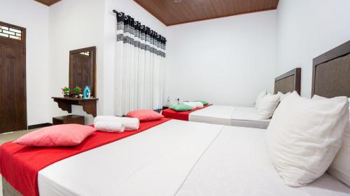 two beds with red and white pillows in a room at Green leaf Villa in Dambulla