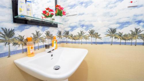 a bathroom with a sink and palm trees on the wall at Green leaf Villa in Dambulla