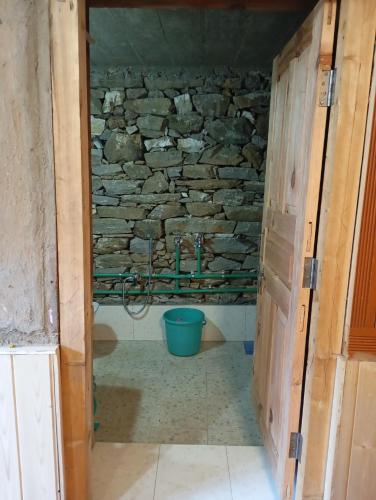 a bathroom with a blue bucket in a stone wall at Sunset Homestay in Sainj
