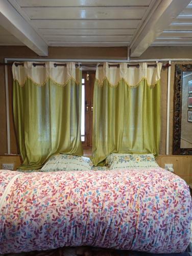 a bedroom with a large bed with green curtains at Sunset Homestay in Sainj