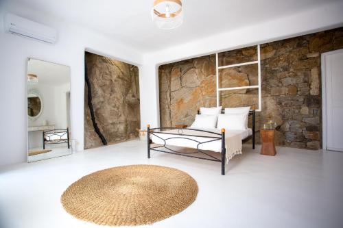 a bedroom with a bed and a stone wall at Maison Haute Mykonos in Ornos